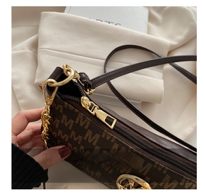 Detail of metal zipper and M-pattern textured synthetic leather on a brown shoulder bag