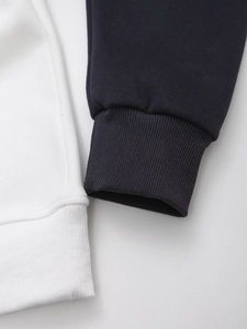 Detail of ribbed cuffs and hem on white and navy knit sweatshirts with fine stitching