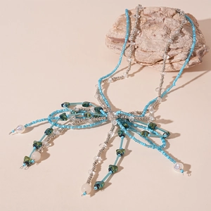 Blue beaded bow necklace with stainless steel accents and tassels on a natural stone