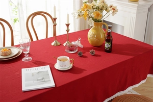 Close-up of red washed cotton tablecloth featuring delicate white lace edge on a table