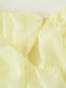 Detailed macro shot of pale yellow pleated chiffon fabric with a translucent button