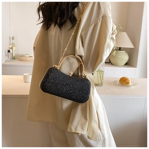 Detail of black sequin clutch with gold metal handle and chain strap for elegant evening wear