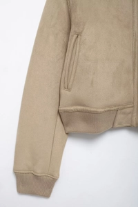 Détail de la veste en daim kaki avec ourlet en maille côtelée et poche latérale discrète