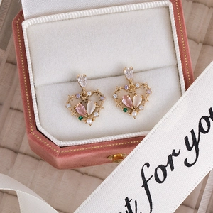 Close-up of heart stud earrings with multi-color zircons and pearl in a pink jewelry box