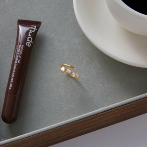 Detalle de anillo de acero inoxidable oro 18K con circonitas blancas en bandeja gris