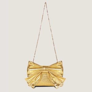 Close-up of golden bow-shaped evening bag featuring woven texture and fine metal chain strap