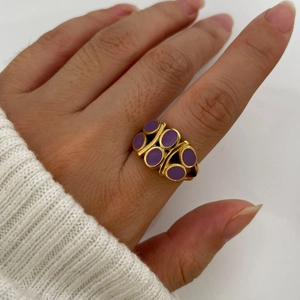 Elegant gold ring with purple enamel oval links worn on finger with a white sweater