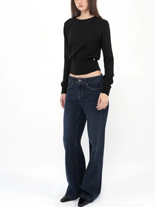 Detail of a slim-fit black wool sweater paired with vintage dark blue wide-leg jeans