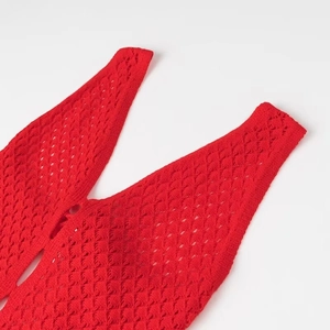Détail de l'encolure en V et de la texture au crochet d'une robe en maille rouge