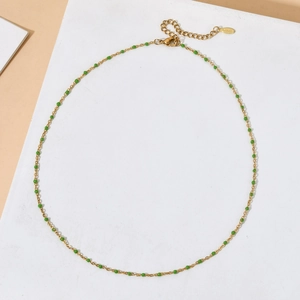 Detail of gold stainless steel necklace with green round beads and lobster clasp