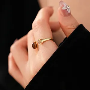 Adjustable gold tiger eye stone ring with cubic zirconia accents on model hand