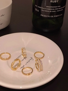 Detailed set of gold bow and pearl rings displayed on a white ceramic plate decoration