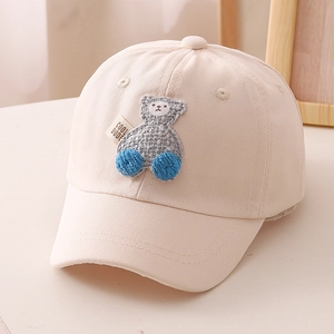 Detail of a cream cotton baseball cap for kids with a bear patch and Cool Dude label