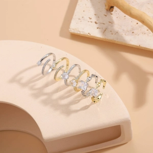 Macro shot of 14K gold and silver geometric rings with sparkling zircon crystals on beige stone