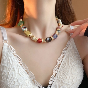 Macro detail of bohemian ceramic floral necklace with gold spacers on female model