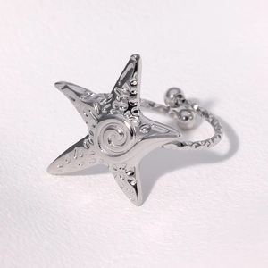 Macro detail of a silver starfish-shaped open ring featuring textured metal dots