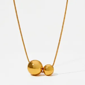 Detail of minimalist gold double ball pendant necklace on a sleek snake chain design