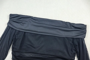 Dettaglio dell'abito in mesh nero trasparente con scollo a barca e trama arricciata