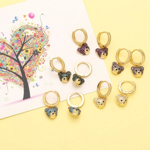 Detailed flat lay of gold bear earrings with colorful zircon micro-inlays on yellow background