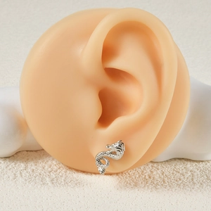 Macro shot of a silver dragon-shaped stud earring worn on an ear model