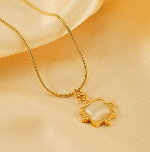 Detail view of a vintage gold snake chain necklace with square gemstone on champagne silk