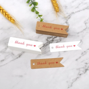 Close-up of brown and white kraft paper thank you tags on a marble texture surface