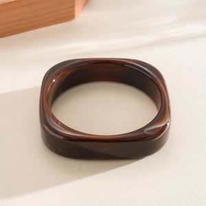 Macro view of a chunky square resin bangle with a brown marbled tortoiseshell finish