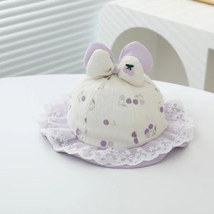 Detail of baby sun hat with purple cherry print, lace trim, and large bow decoration