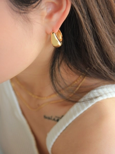 Close-up of a model wearing stylish gold teardrop hoop earrings with a glossy metal finish