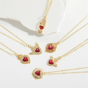Detail view of six vintage gold plated heart pendants with red zircon and retro wing motifs