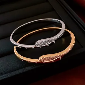 Minimalist gold and silver snake crossover bangles with pavé cubic zirconia accents