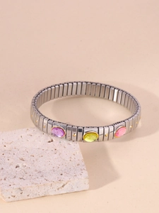 Detail of stretch stainless steel bracelet with three-color oval gemstones on white stone
