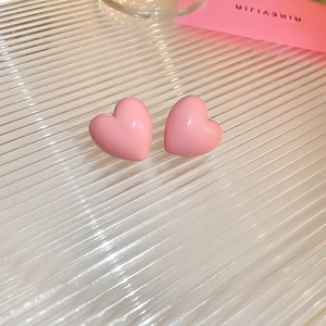 Macro view of polished pink acrylic heart stud earrings with silver needles for women