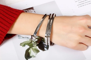 Detail of silver triple-layered angular bangle on wrist with stylish knit background
