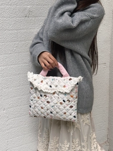 Detail of quilted cotton laptop bag with cartoon print and pink handles on model