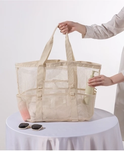 Detailansicht der beigen Strandtasche aus Netzgewebe mit praktischen Fächern für die Reise