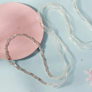 Luxury rhinestone bridal headband with elegant white organza ribbon ties on blue background