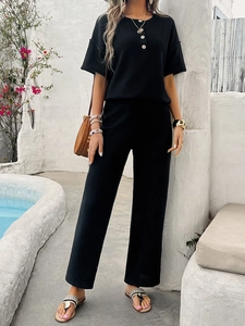 Detail of a black knit two-piece set featuring short sleeve top with buttons and long pants
