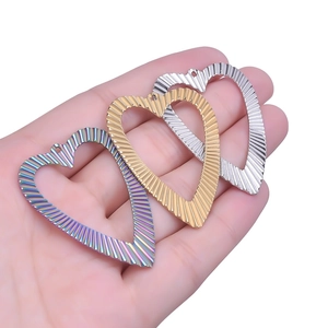 Three striped heart pendants in rainbow, gold, and silver finishes shown on hand