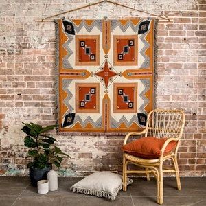 Detail of bohemian geometric woven blanket with fringes hanging on a brick wall