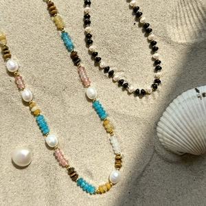 18k gold stainless steel bead necklace with pearls and colorful gems on a beach