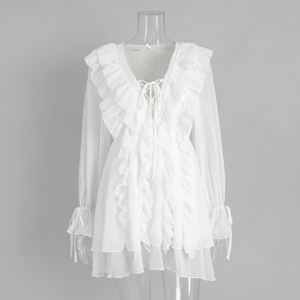 Detail of white chiffon mini dress featuring tiered ruffles and lace-up V-neckline