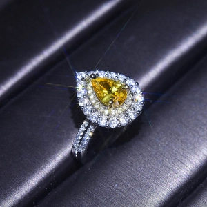 Macro shot of silver ring featuring a pear-cut yellow gemstone with halo diamond setting
