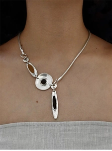 Detail of silver metallic disc necklace with dark enamel inlay on a snake chain