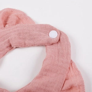 Pink muslin cotton baby bib with ruffled edge and snap closure shown on white background