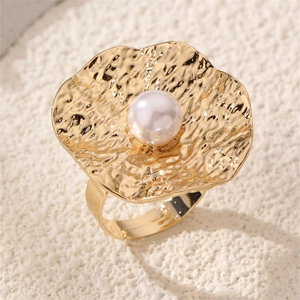 Detail of a golden flower wave ring featuring hammered metal texture and a large white pearl