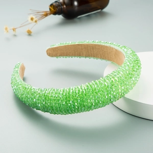 Detail of light green crystal padded headband featuring dense sparkling beads on a stand