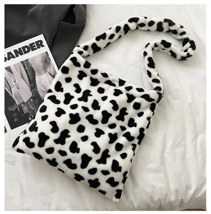 Detail of soft faux fur shoulder bag with black and white cow print texture and fluffy finish