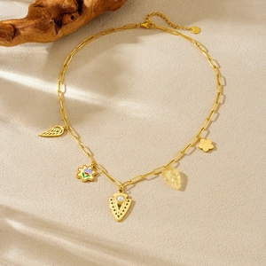 Gold stainless steel necklace with wing flower and pearl triangle charms on beige surface