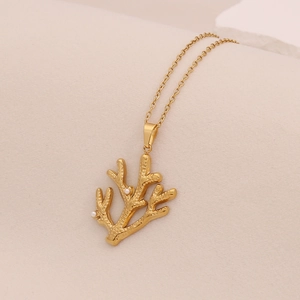 Detailed view of a golden coral pendant with white pearl accents on a fine metal chain